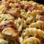 Bowl of creamy Chicken Bacon Ranch Pasta topped with crispy bacon and herbs