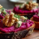Creamy beet and walnut spread crostini topped with fresh herbs