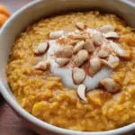 A bowl of warm vegetarian pumpkin oats topped with nuts and spices.