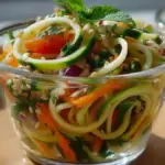 Colorful zucchini noodle salad cups filled with fresh vegetables and light dressing.
