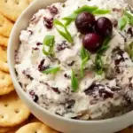 Whipped cranberry feta cheese dip served in a bowl with crackers.