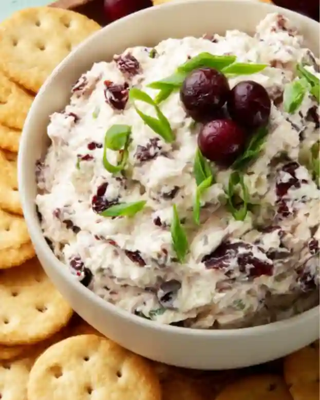 Whipped cranberry feta cheese dip served in a bowl with crackers.