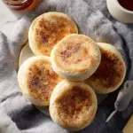 Freshly baked homemade English muffins on a wooden table