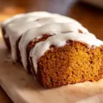 Pumpkin bread slice topped with cream cheese frosting and sprinkled cinnamon
