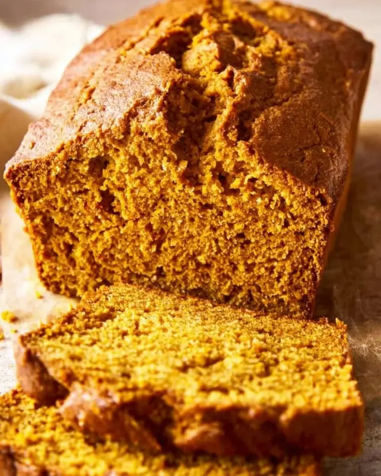 Sliced vanilla pudding pumpkin bread on a wooden cutting board.