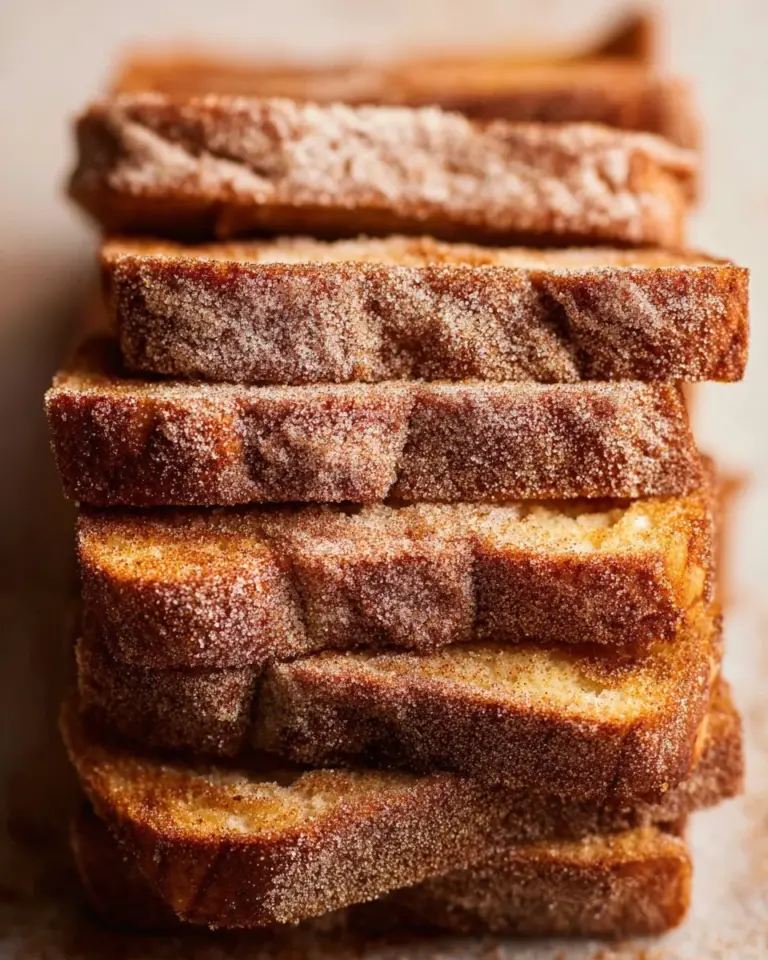 Sliced apple cider donut bread on a wooden board with cinnamon sugar topping.