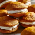 Delicious Pumpkin Whoopie Pies with cream filling on a wooden table