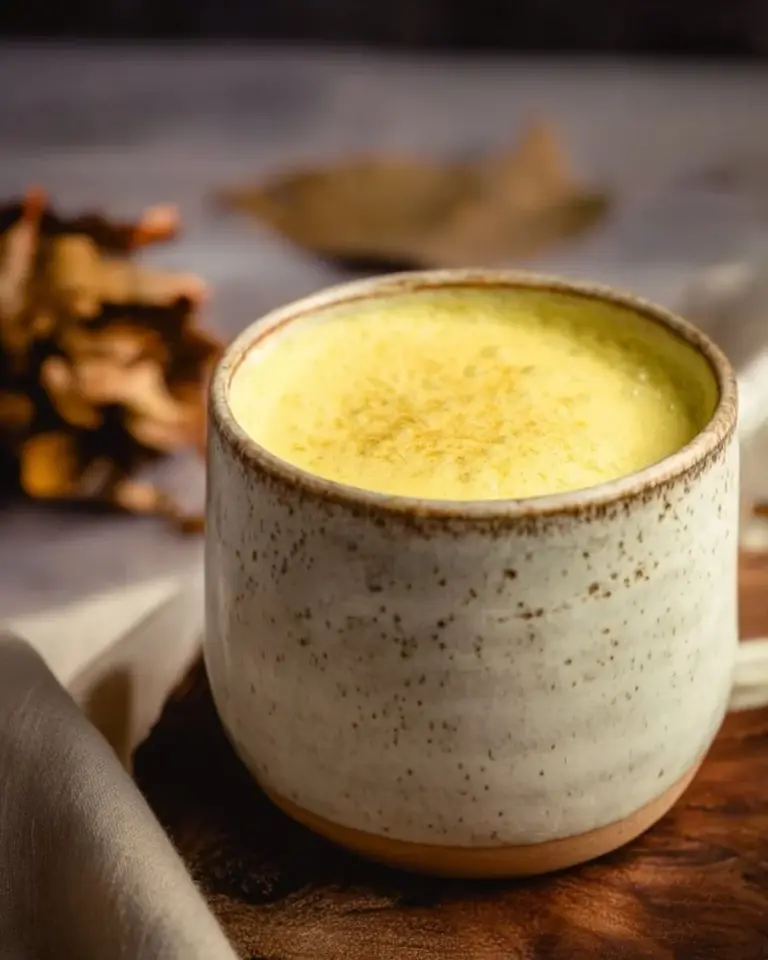 A steaming cup of spiced turmeric latte topped with cinnamon.