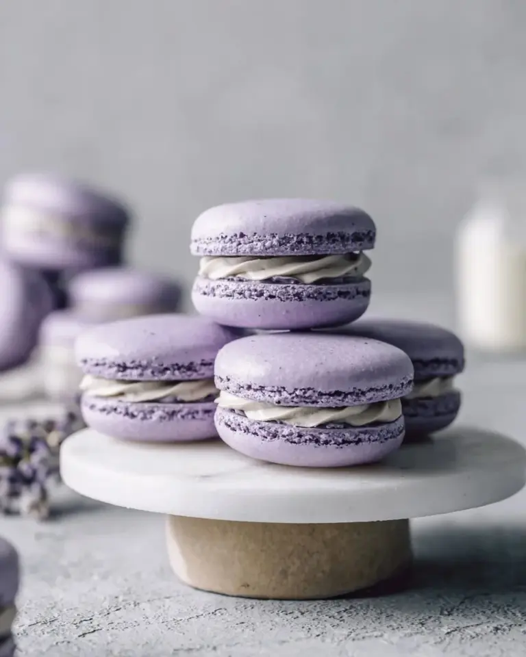Assorted colorful French macarons on a decorative plate.