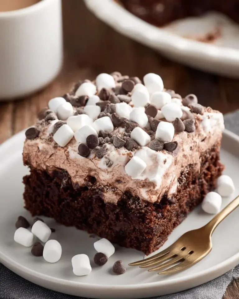 Delicious hot chocolate poke cake topped with whipped cream and chocolate shavings