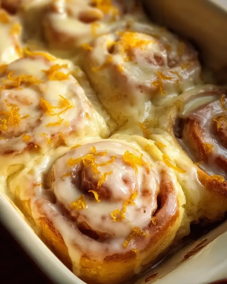 Homemade orange rolls with citrus glaze on a baking tray.