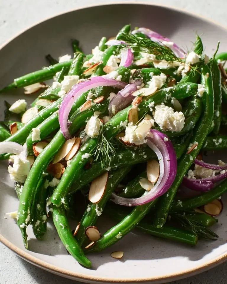 Fresh green bean salad topped with feta cheese in a bowl