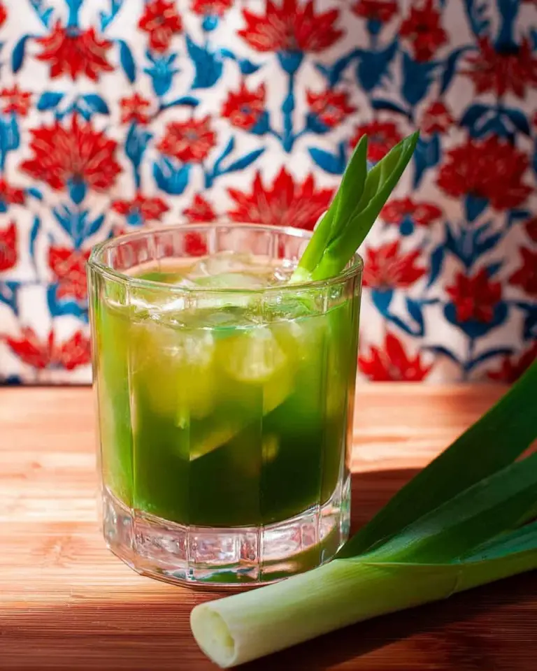 A refreshing glass of Pandan Lemongrass Jelly Iced Tea garnished with herbs.