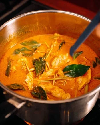 A bowl of quick and easy Thai red chicken curry garnished with fresh herbs.