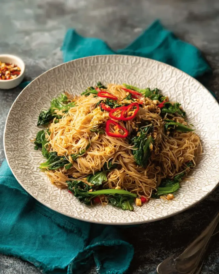 Stir-fried wide noodles and rice vermicelli dish garnished with vegetables.